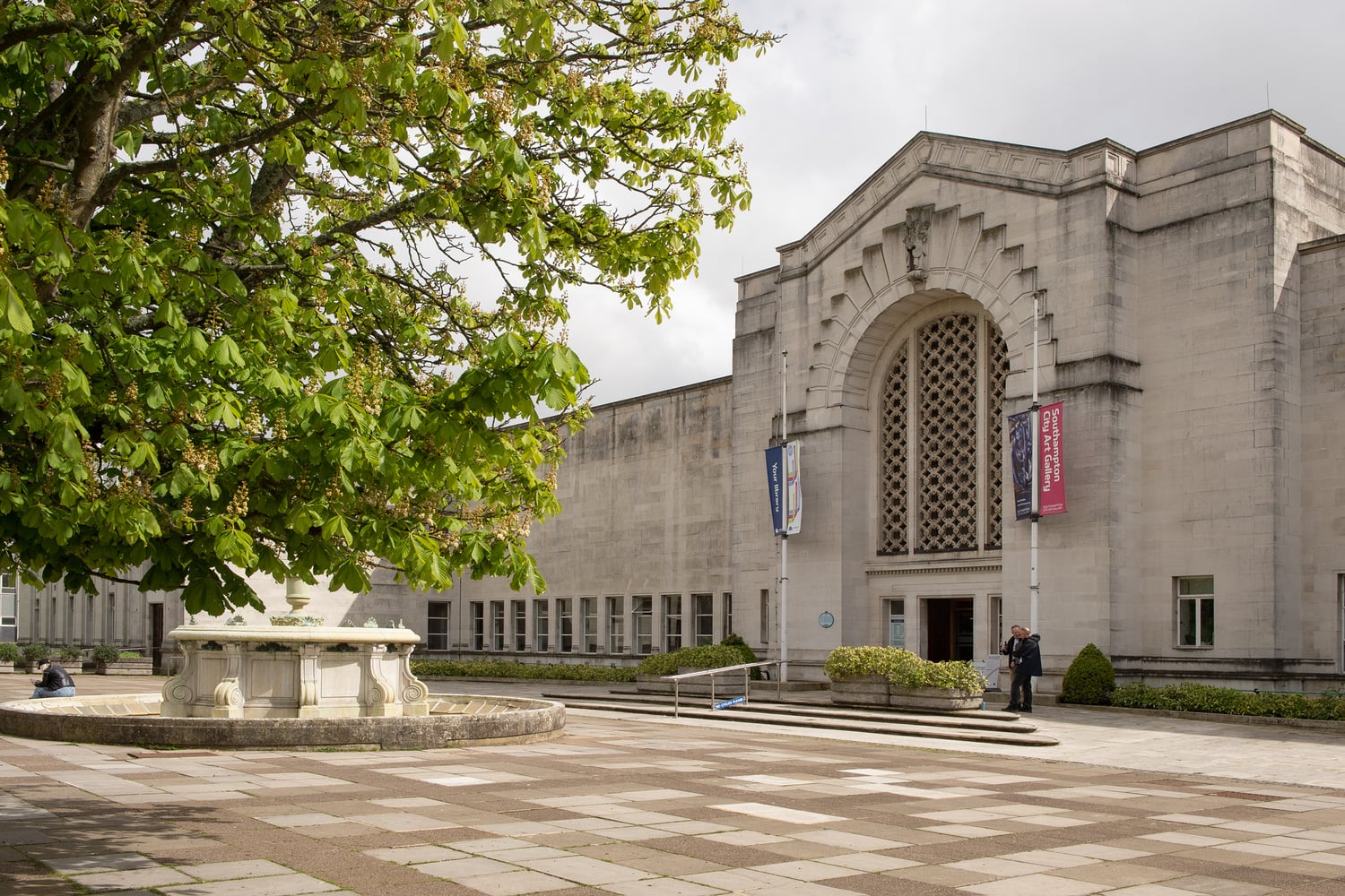 A fountain and tree outside the historic Southampton City Art Gallery building.