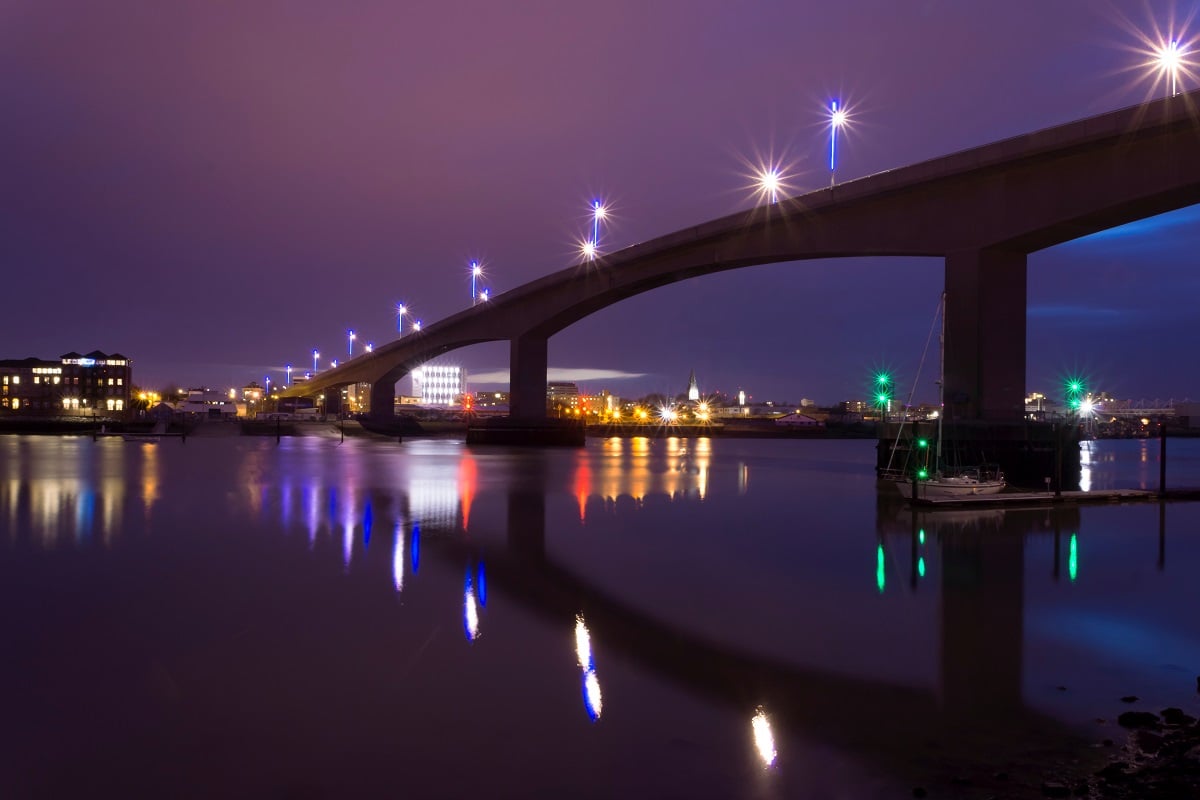 Itchen Bridge over still water in Southampton at night, with light reflected on the water.