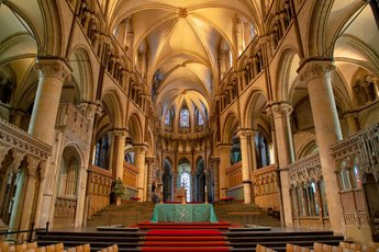 Inside Canterbury Cathedral, with an altar and red carpet.