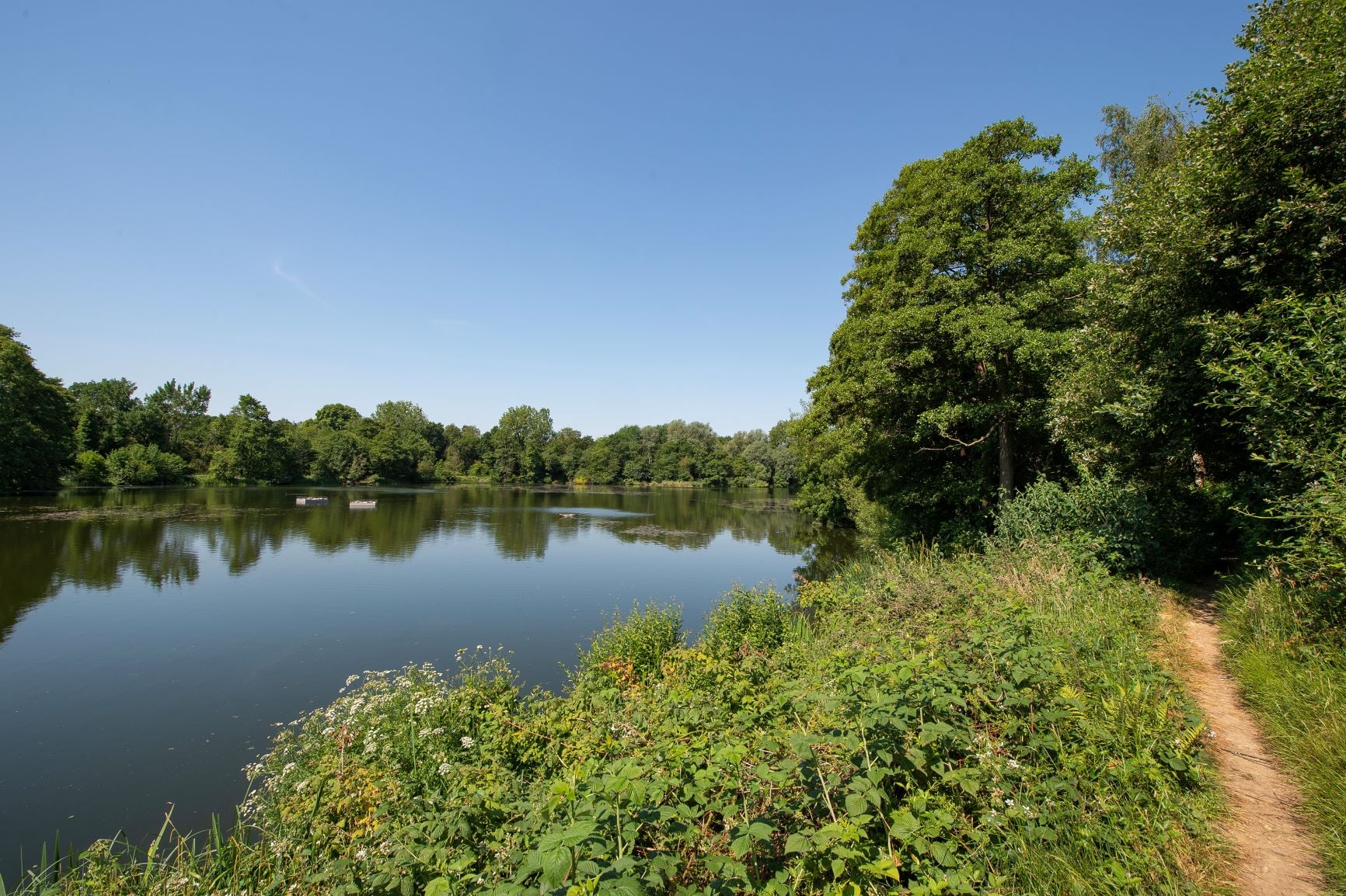 A small path lines the edge of a vast waterway near Dunton Green.