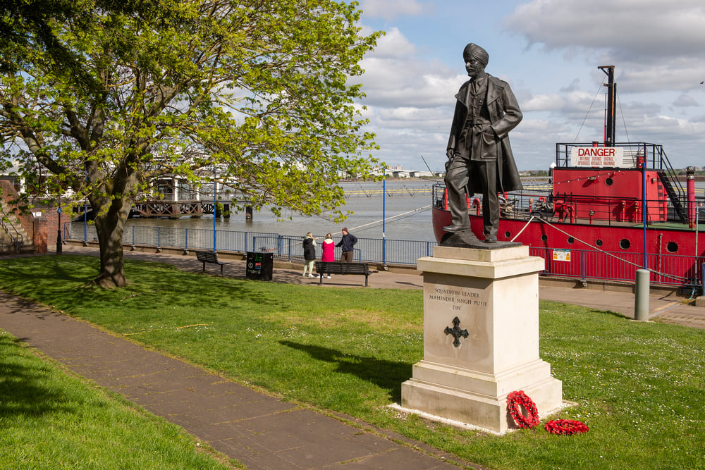 a statue of a person on a pedestal by a body of water
