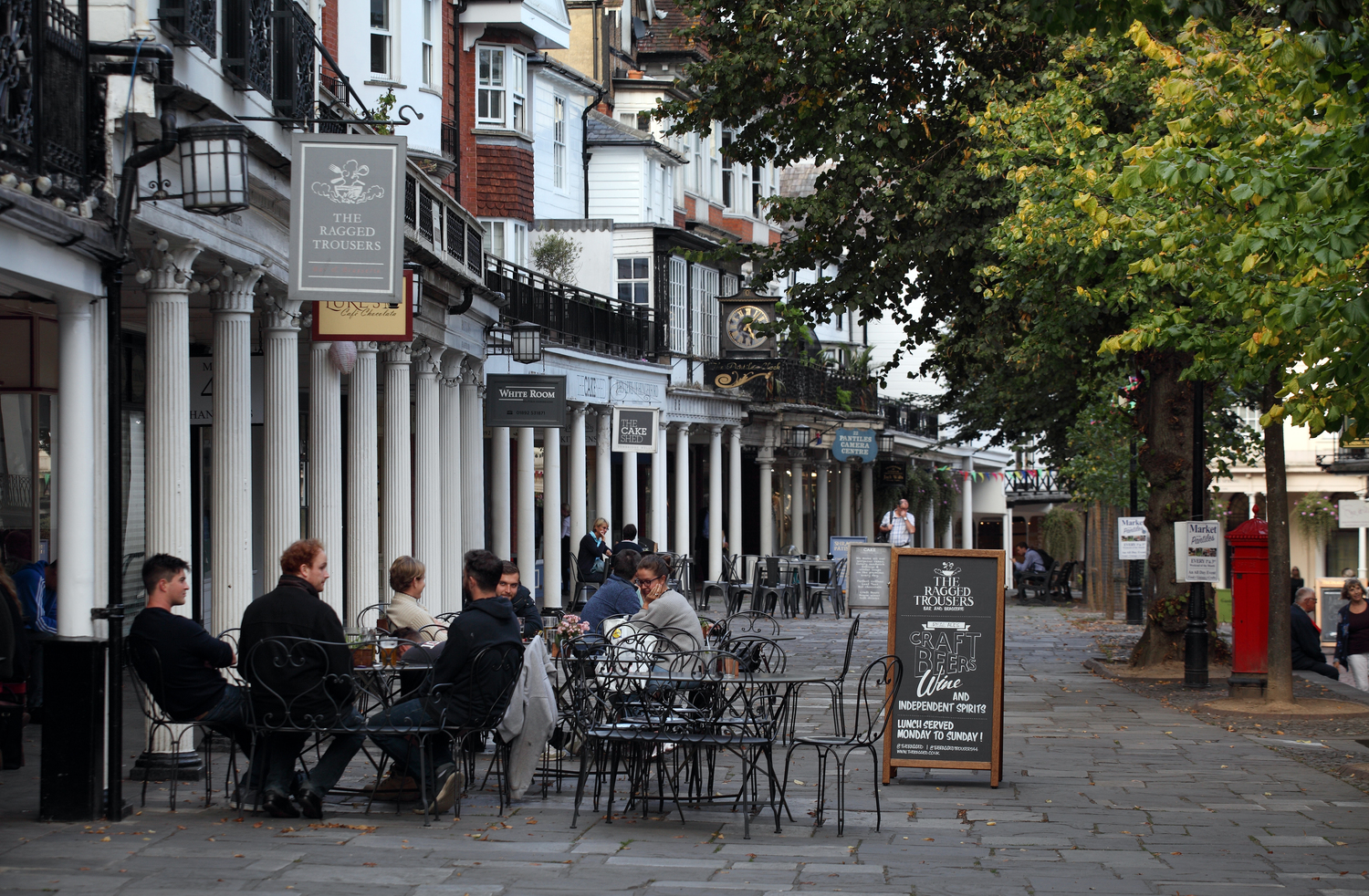 People sitting at tables outside with The Pantiles in the background