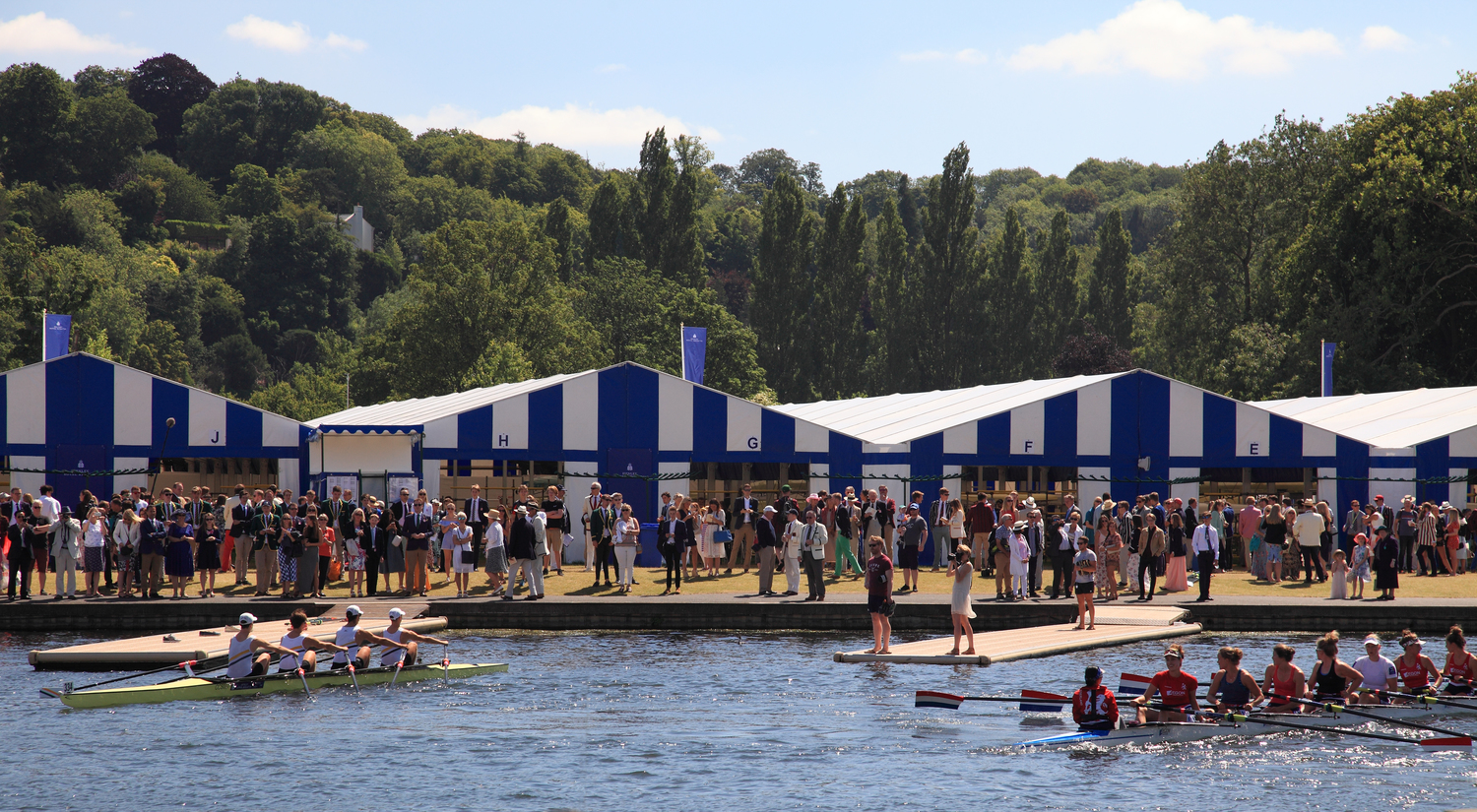 A crowd of people watching two teams boat race.