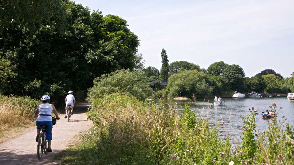 people riding bikes on a path by water