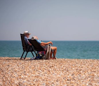 a man and woman sitting in chairs on a beach