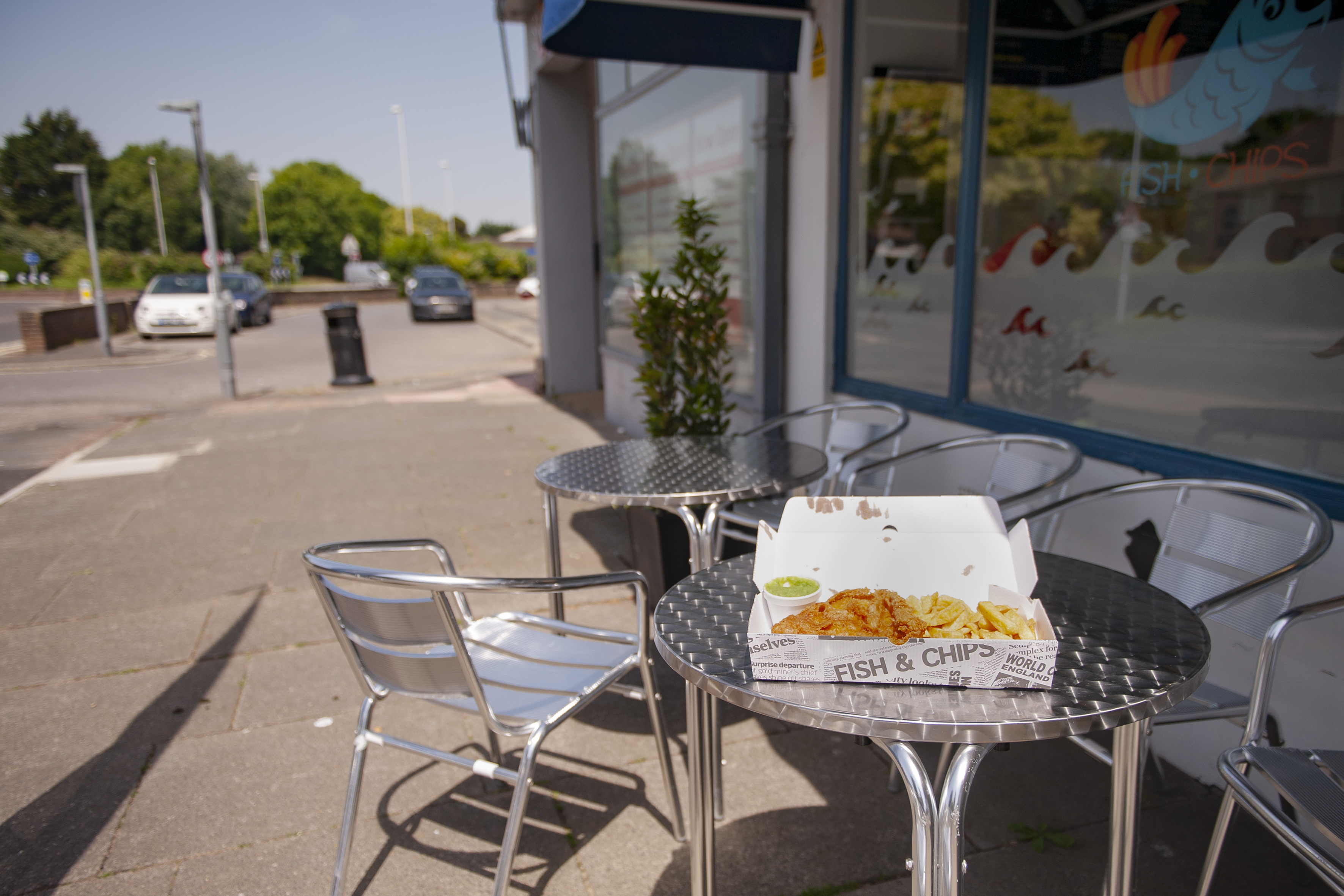 An open box containing Fish and Chips sits atop a metal table outside of a local fish and chip shop on Goring Highstreet.