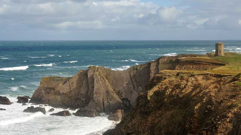 a rocky cliff with a body of water in the background