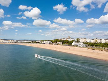 The seafront in Exmouth, with a boat and a green fields across the bay