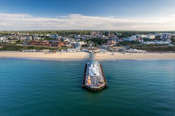 An aerial view of Bournemouth Pier from the sea with the town and beach in the background.