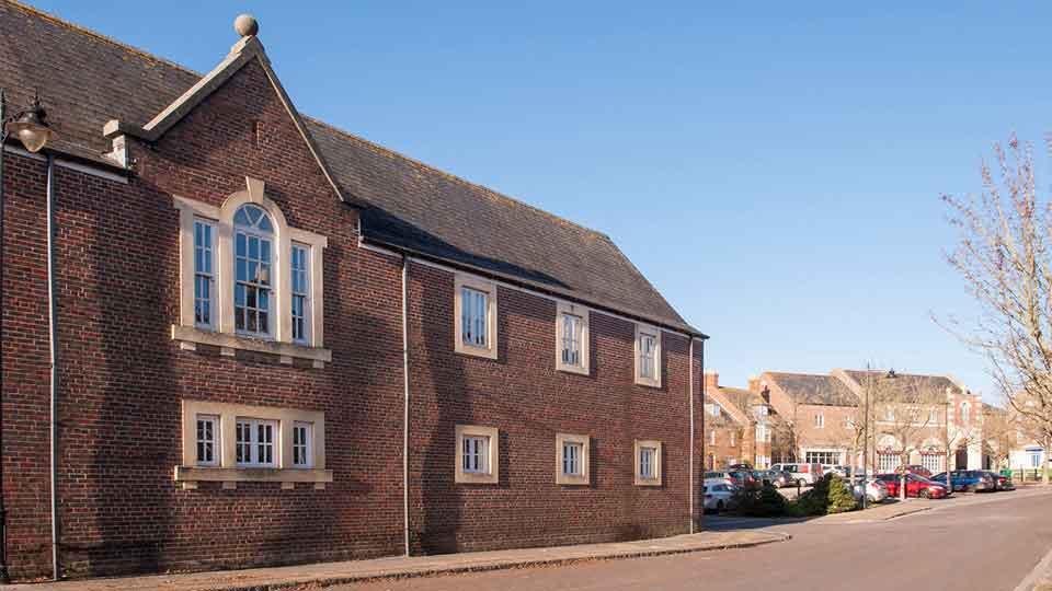 a brick building with a street and cars parked on the side