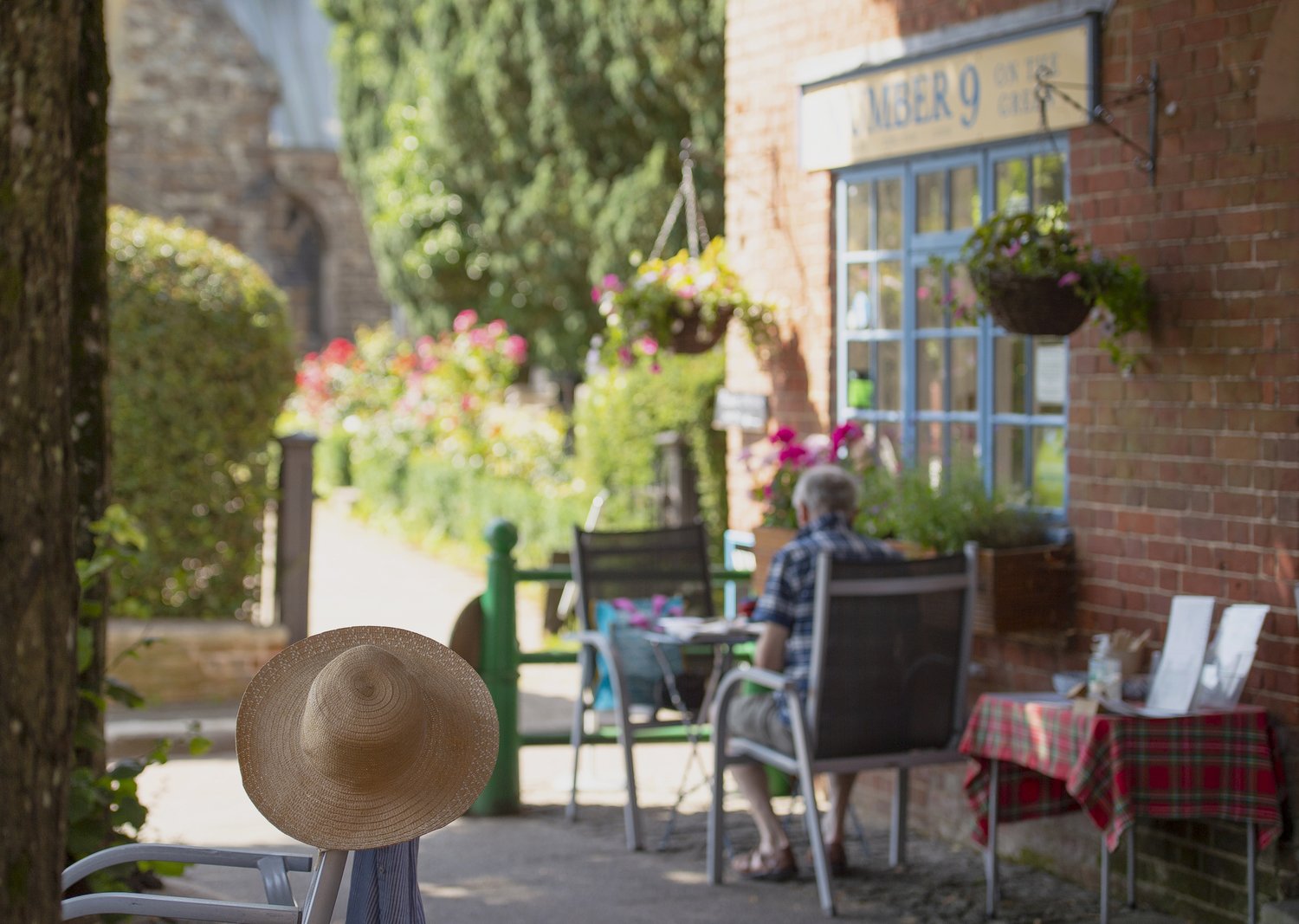 A retired person sits at a table in front of Number 9 cafe in Wimborne Minster, Dorset.