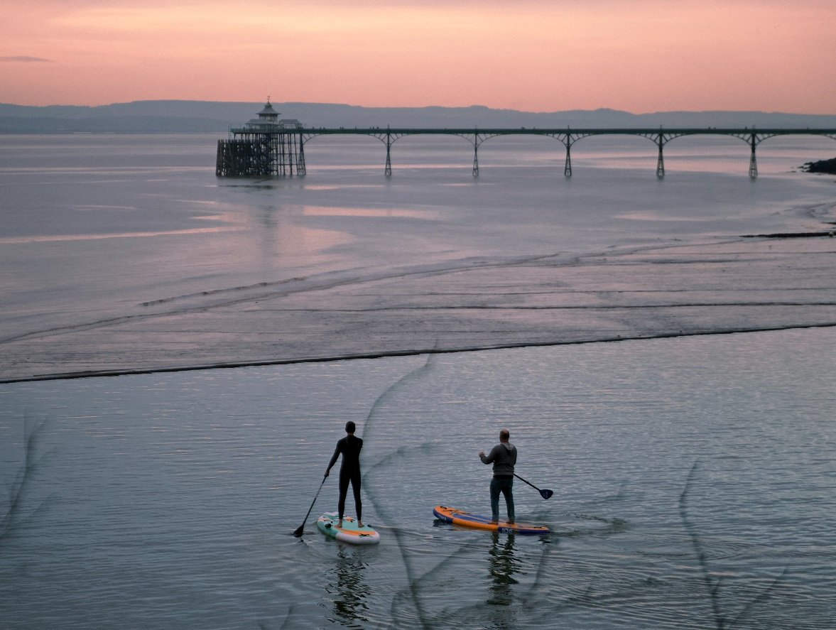 Paddleboarders in front of Clevedon pier at sunrise