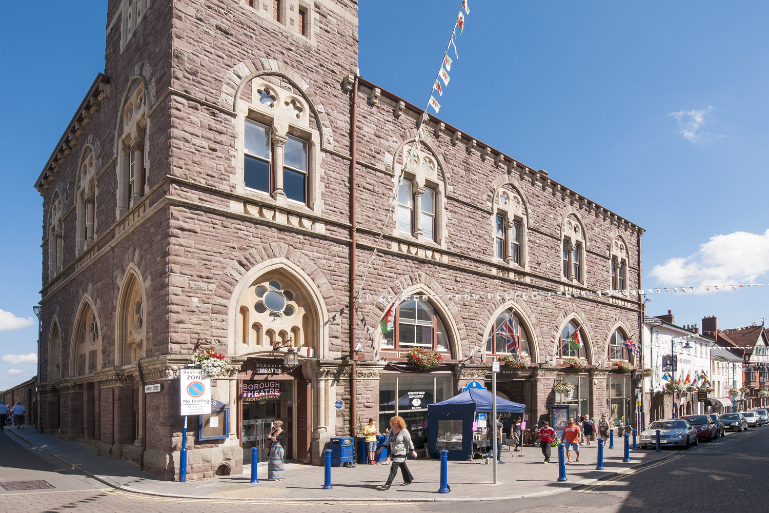 People walk outside Borough Theatre and Market Hall in Abergavenny, Wales.