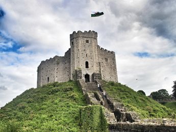 a stone castle on a hill with Cardiff Castle in the background