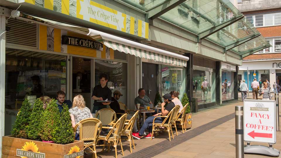 people sitting at tables outside a restaurant