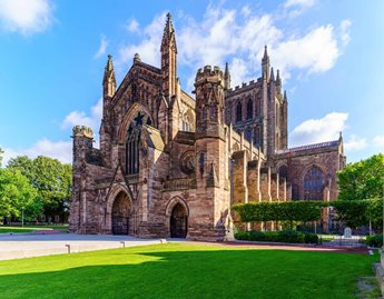 a large brick building with towers with Hereford Cathedral in the background