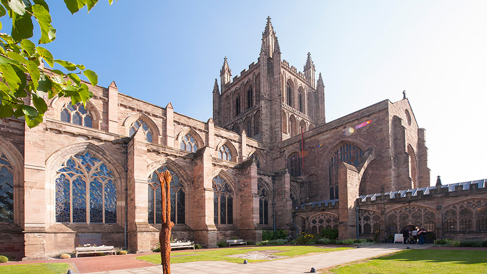 a large building with a tree in front of it with Hereford Cathedral in the background