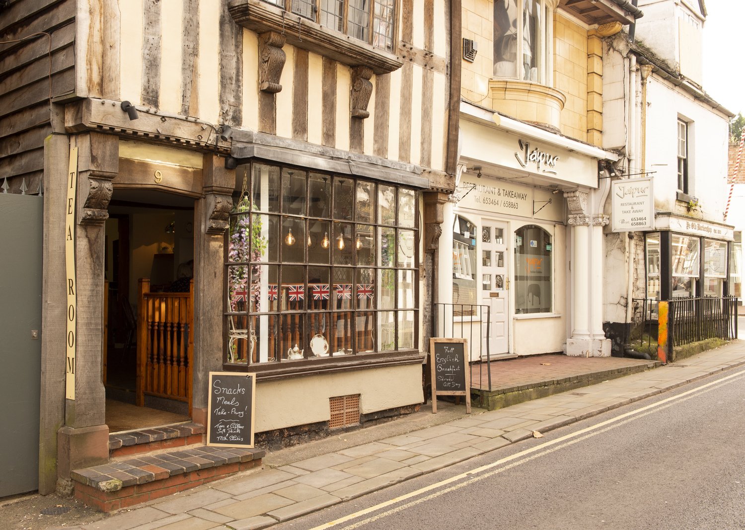 Exterior of a public house and shop on a terraced road in Market Drayton.