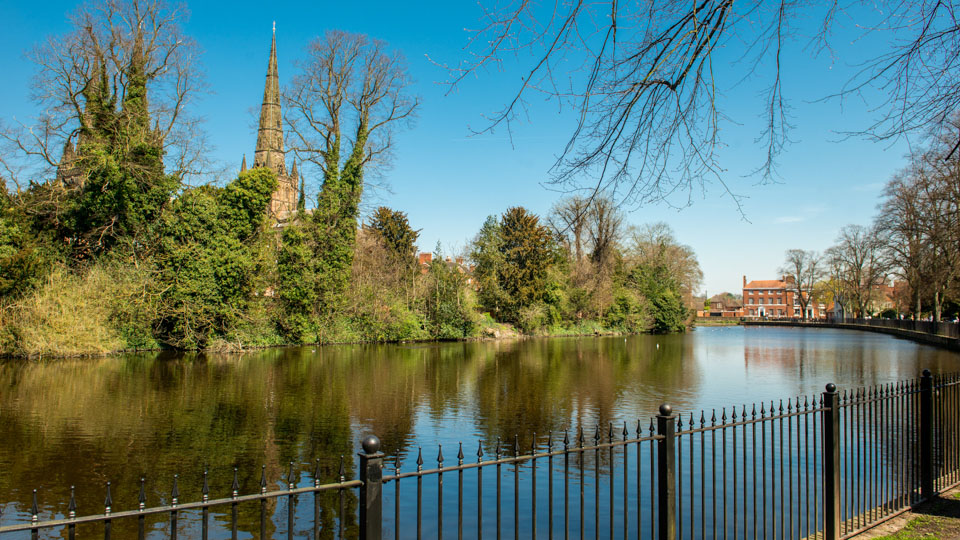 a body of water with a fence and trees around it