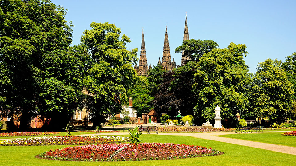 a garden with trees and a castle in the background