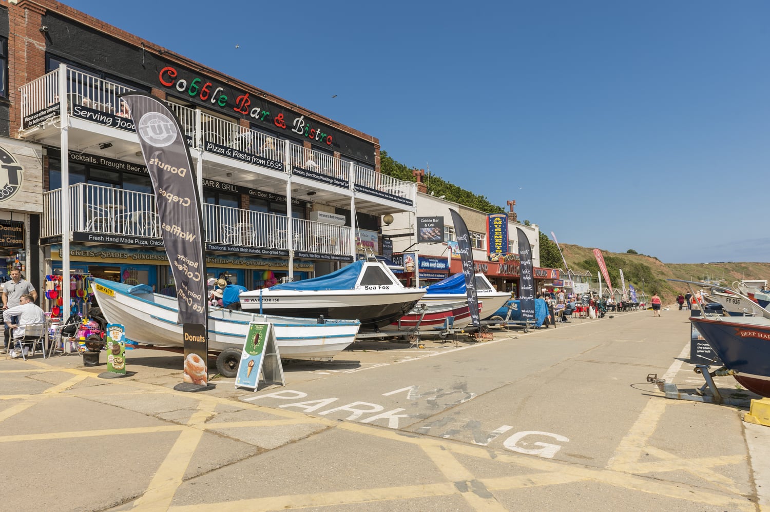 Small boats line the exterior of the Cobble Bar & Bistro in Filey, near the beachfront.