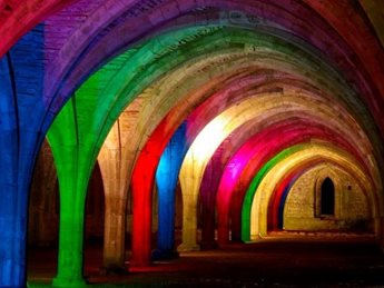 A historic building in North Yorkshire, illuminated with multicoloured lights.