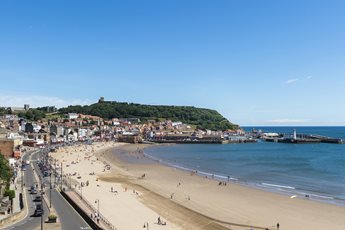 A view across South Bay Beach with people on it and Scarborough town buildings in the background.