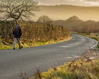 A retiree strides out for a sunny early morning walk along the road across Baildon Moor.