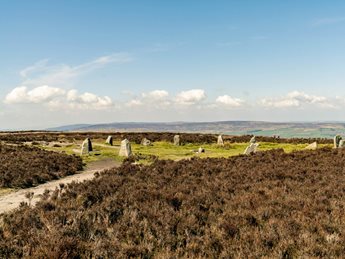 a field of grass with a stone structure in the distance