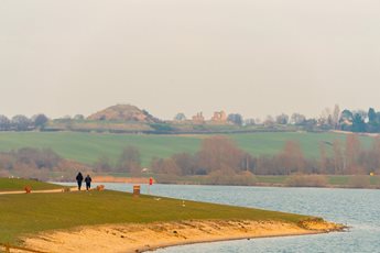 a grassy area with a body of water and a hill in the background