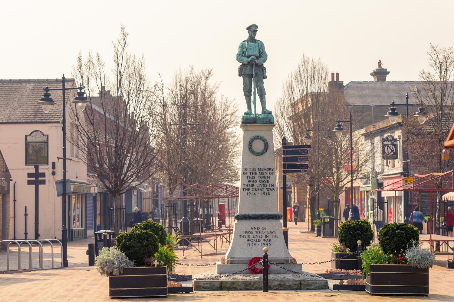 a statue of a person with a hat on a pedestal in a town