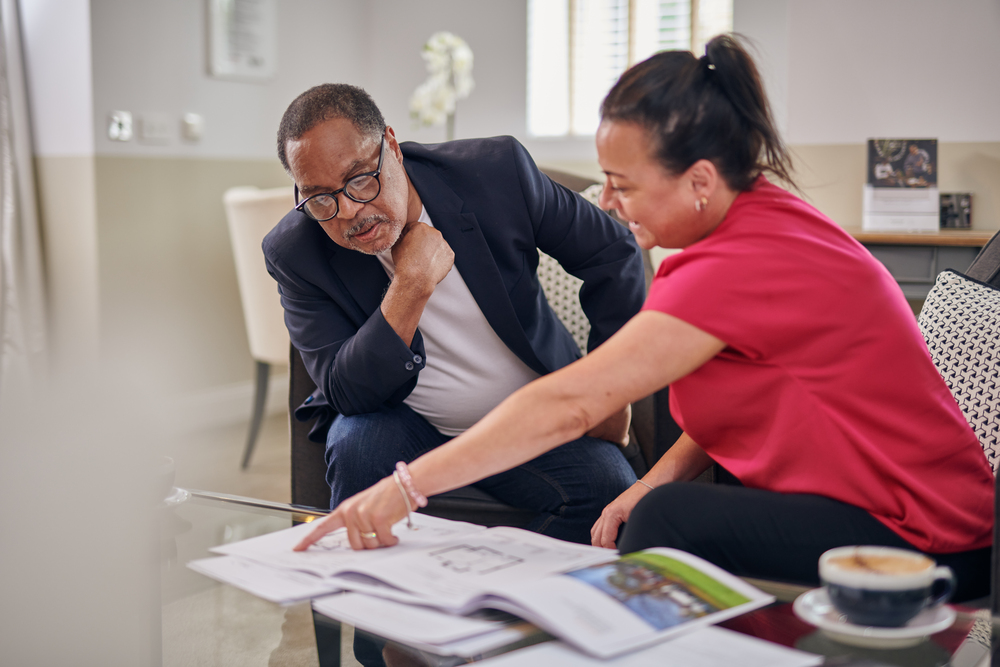 A potential homeowner sitting with a sales consultant looking at McCarthy Stone product offerings.