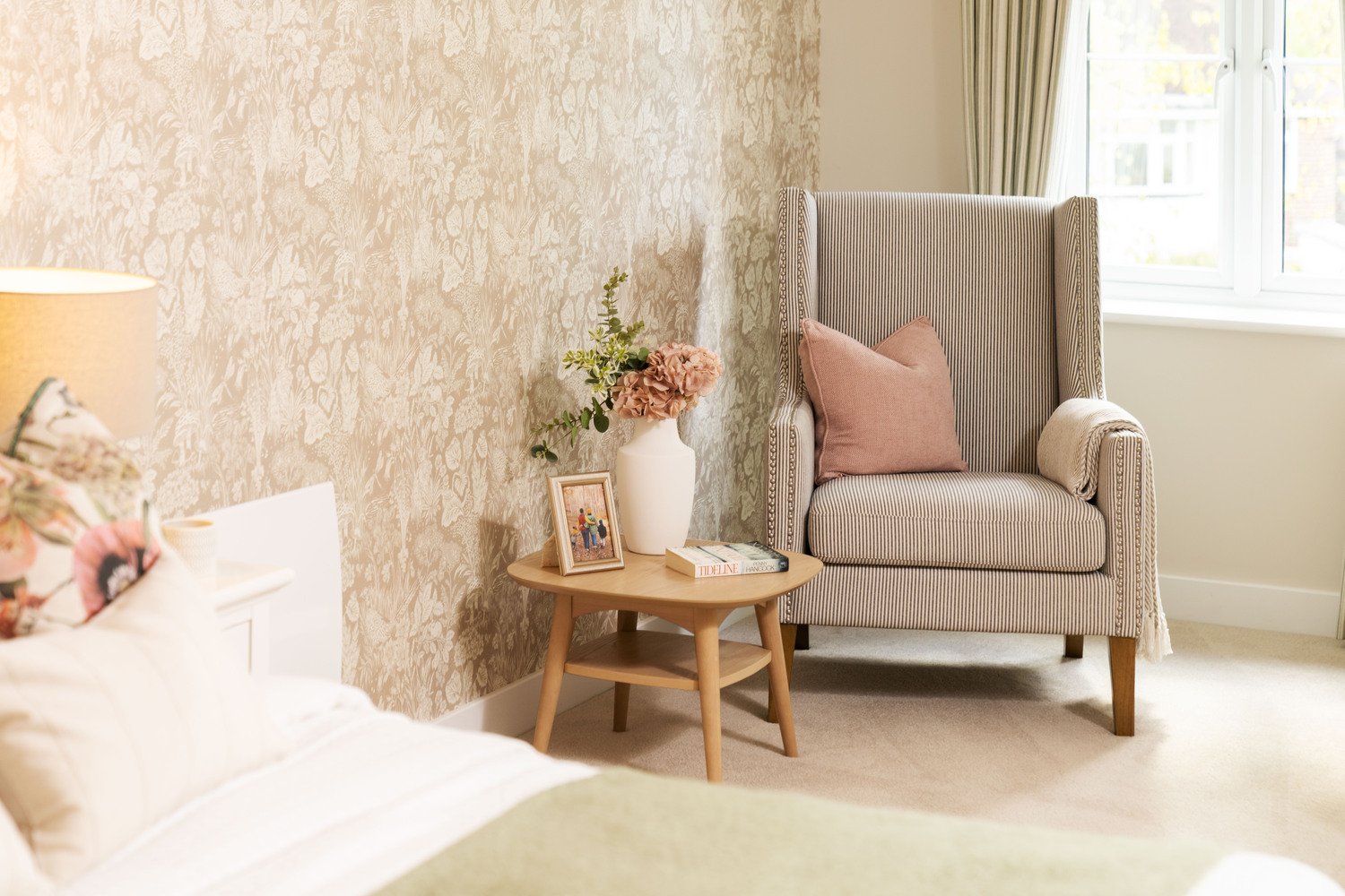 A beautifully bedroom in a McCarthy Stone retirement apartment, featuring a stylish seating area with an armchair and cushions.