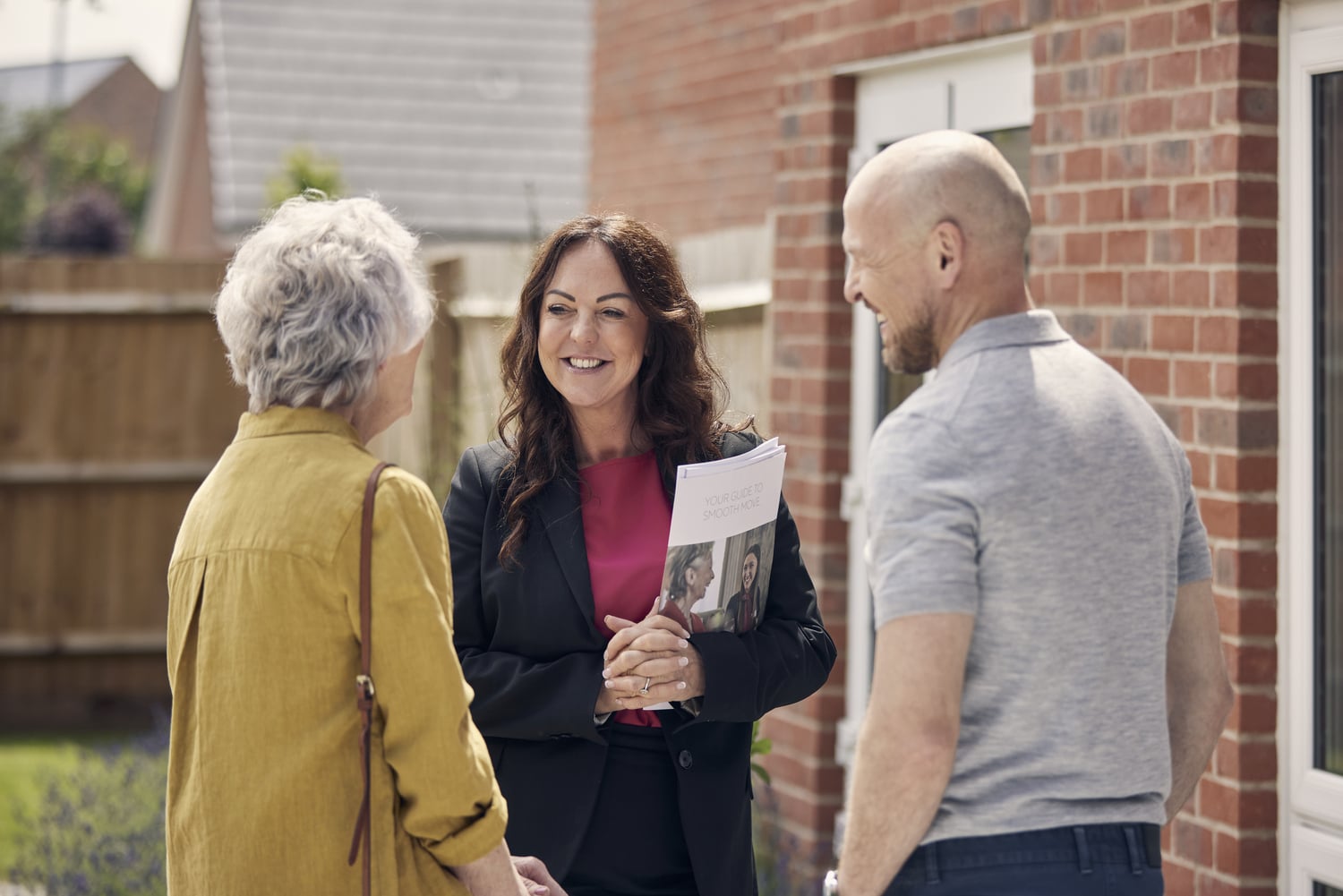 Elderly woman with adult son speaking to staff member holding documents.