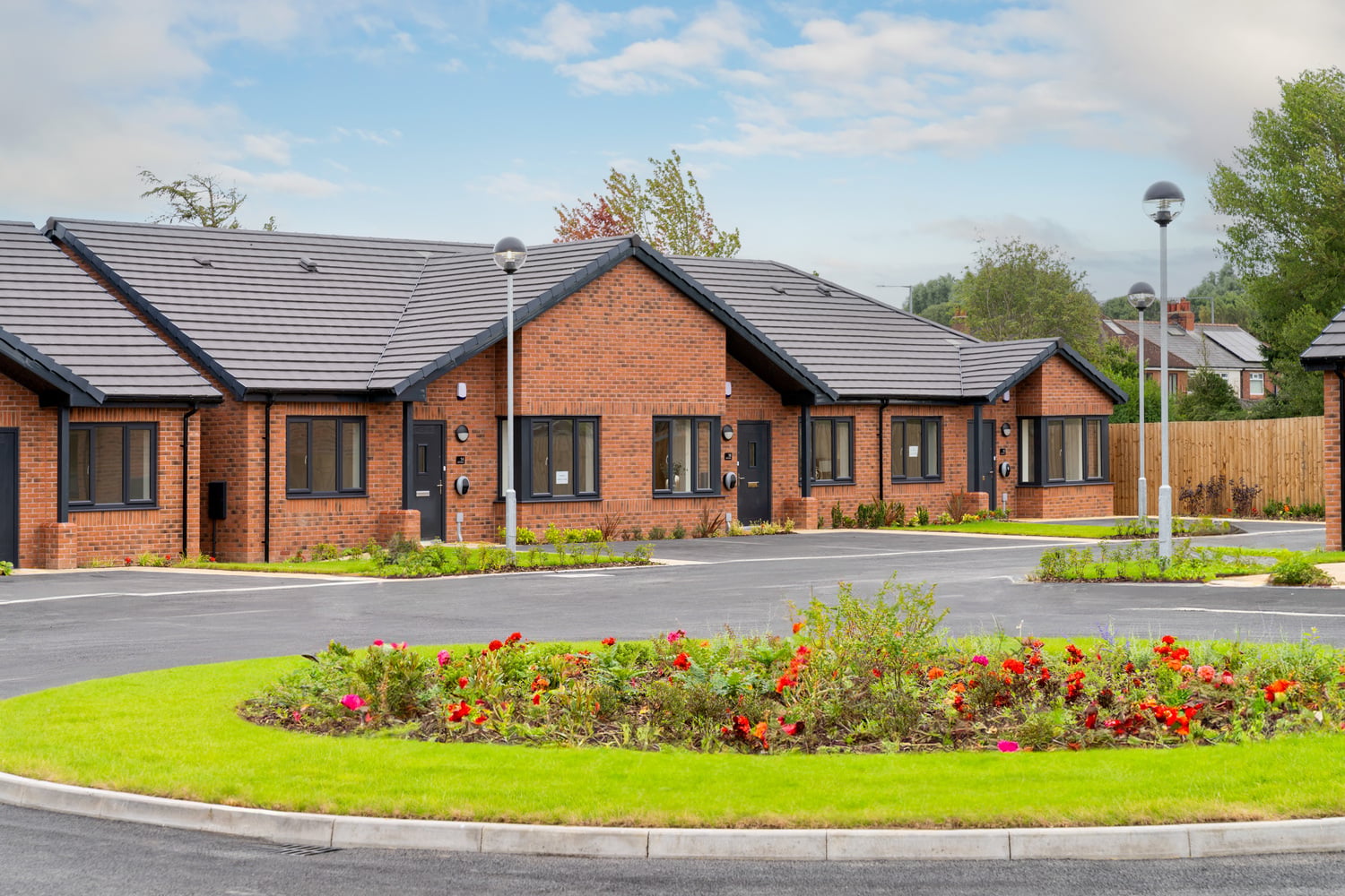 Maintained front gardens and landscaped mini roundabout outside McCarthy & Stone retirement bungalows.