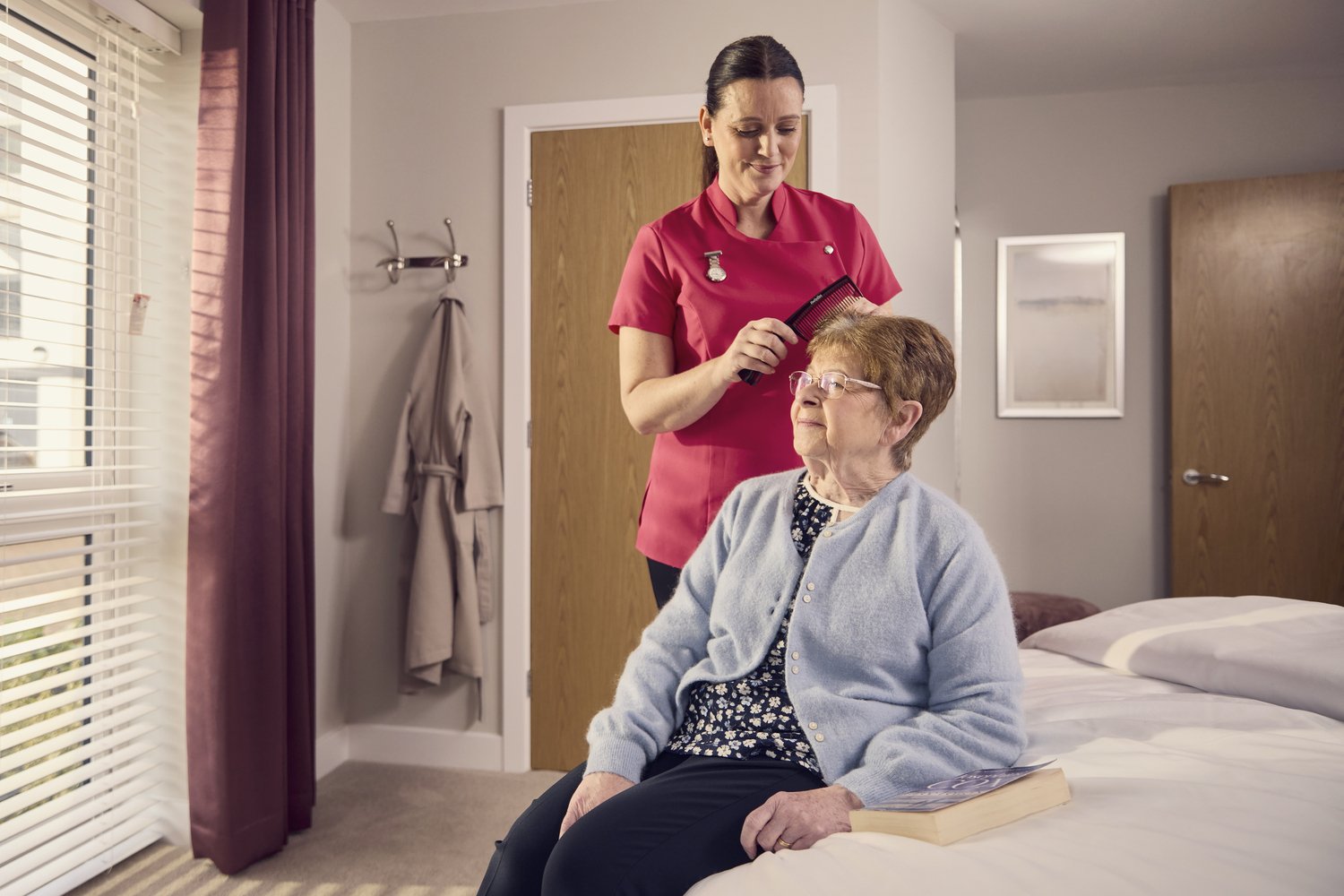 A McCarthy Stone support worker helping a retired lady style her hair.