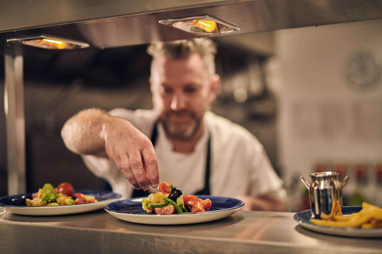 A chef plates up fish in a McCarthy Stone assisted living retirement living bistro.