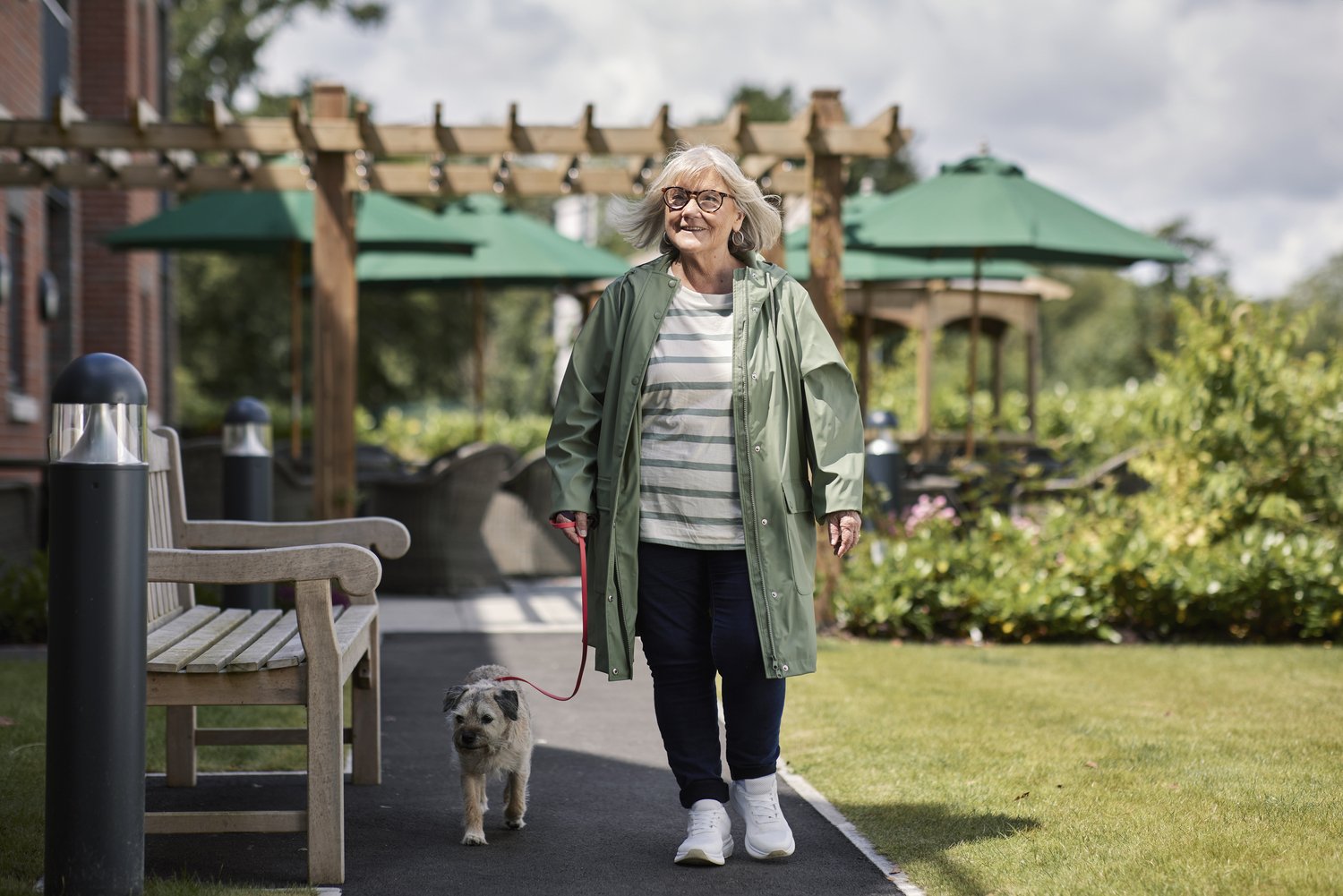 A retired lady walking her dog in the gardens of a McCarthy Stone development.