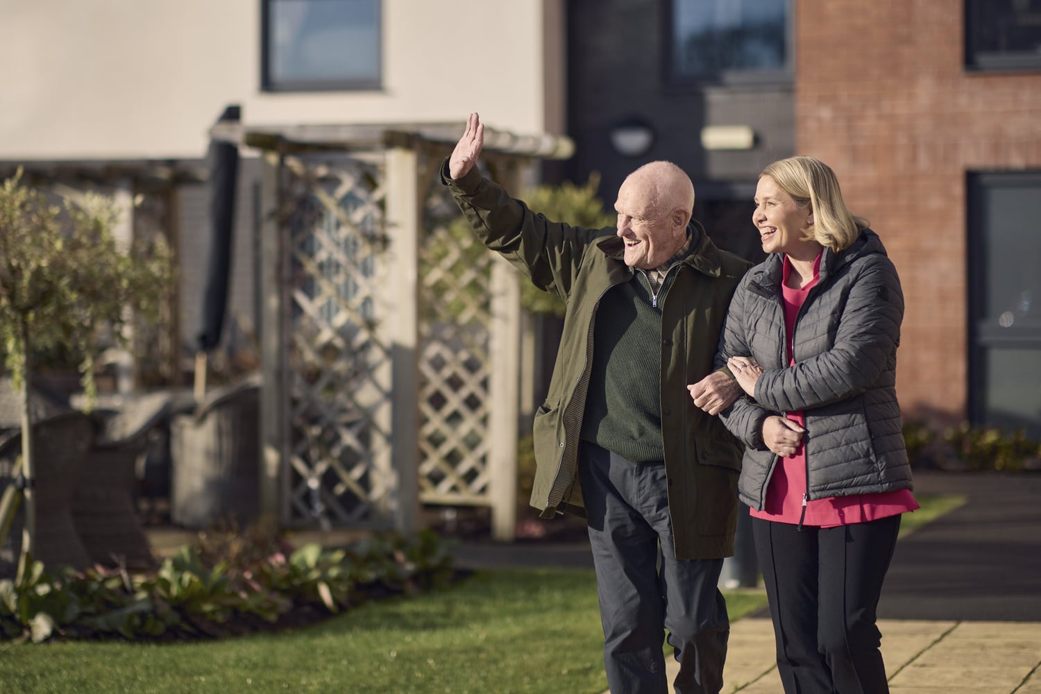 A carer walking in the gardens of a McCarthy & Stone development with a homeowner.