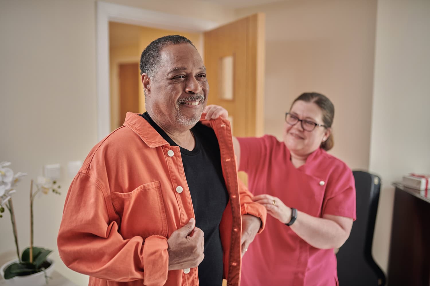 A friendly member of the McCarthy Stone team helping a senior resident to get dressed in their retirement home