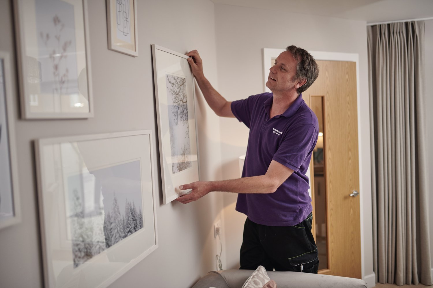 An individual hanging pictures and taking care of handy tasks around the retirement home. 