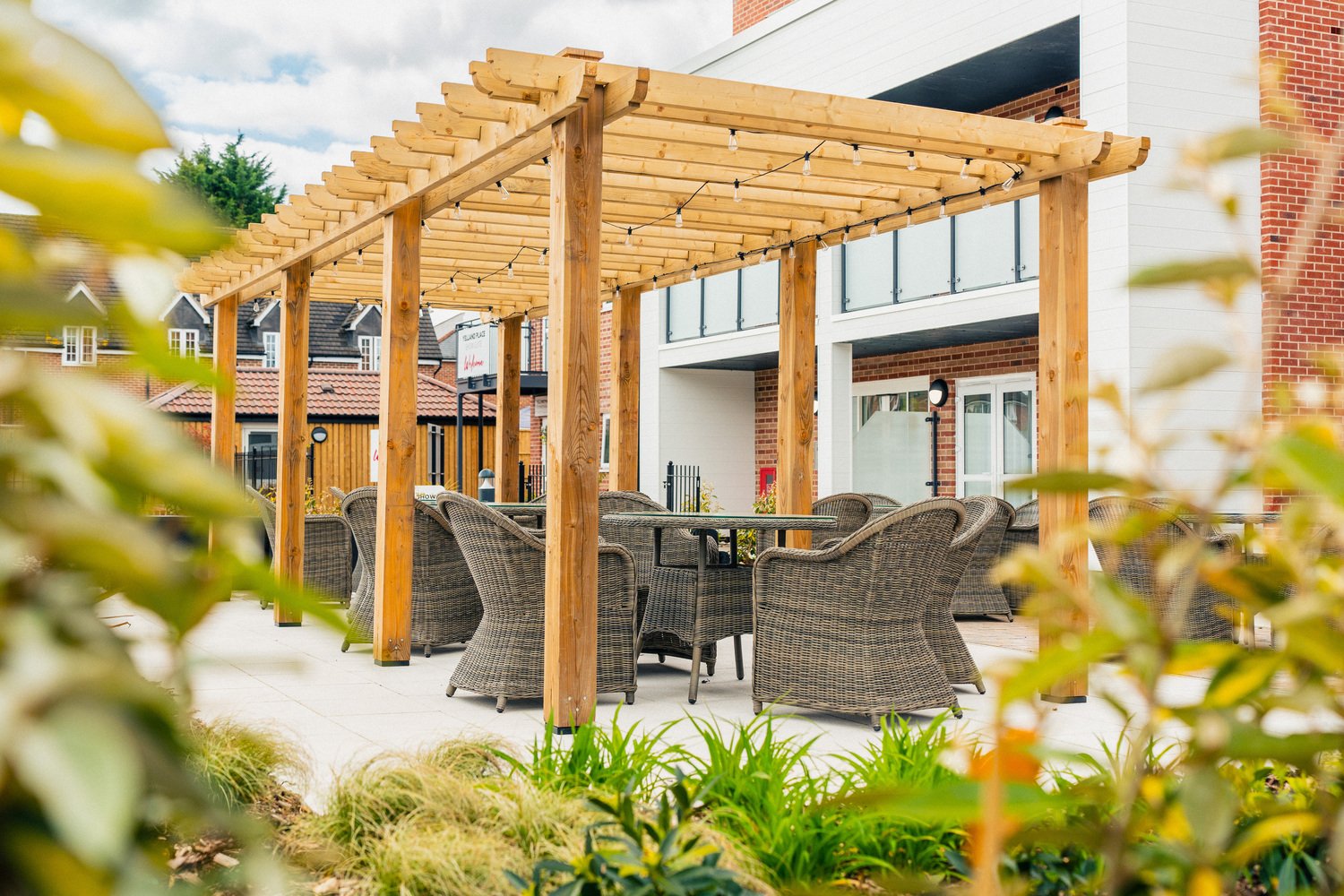 The outdoor area of a development by McCarthy Stone. The patio features a stylish outdoor seating area for residents to socialise. An array of plants line the outskirts of the garden to enhance privacy
