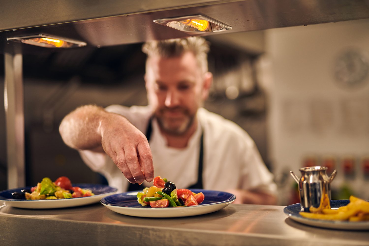 A chef adding the final touches to a dish, ready to be served to a guest at the McCarthy Stone bistro