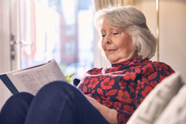 Senior woman sits and reads in her McCarthy Stone over 60s independent living apartment